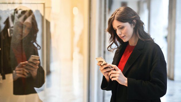Bild einer Frau in einem Geschäft mit Smartphone in der Hand.